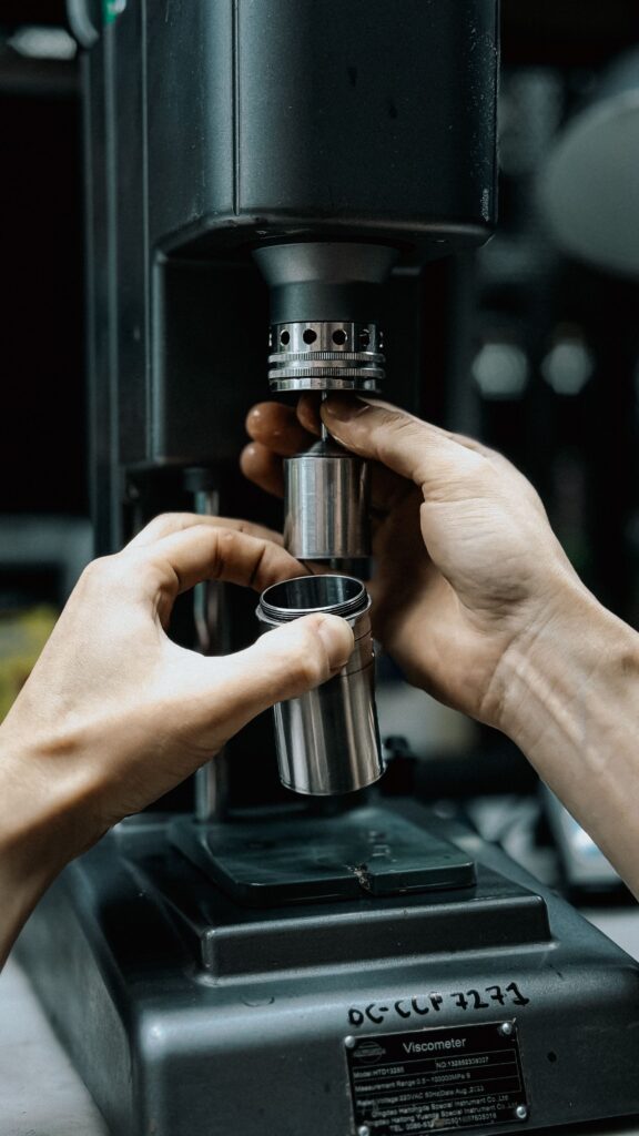 A detailed shot of hands adjusting a viscometer in a laboratory setting.